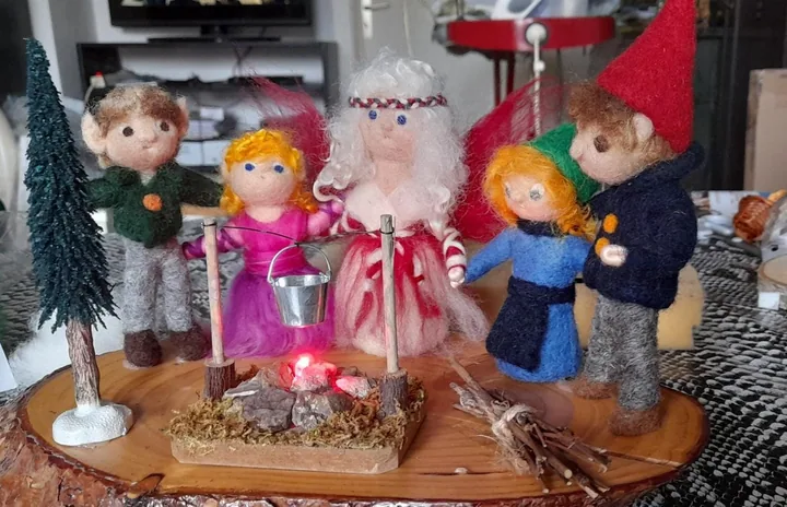 Eine Figurengruppe versammelt sich um ein leuchtendes Lagerfeuer.